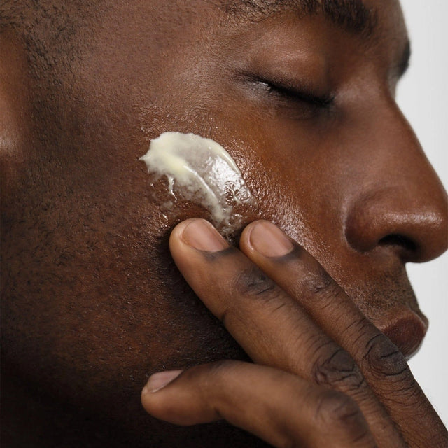 Close-up of a man massaging the rich texture of the After Dark Restorative Night Serum into his cheek.