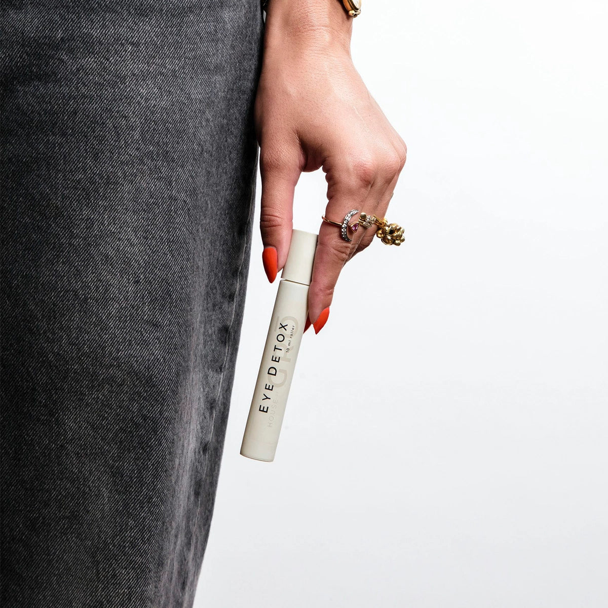 Hand holding the House of GRŌ Eye Detox Brightening Oil roller to show its compact size and elegant design.
