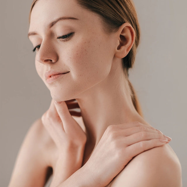 Relaxed woman gently touching her neck and collarbone, highlighting the soothing and calming benefits of the House of GRŌ Feel Relief Salve.